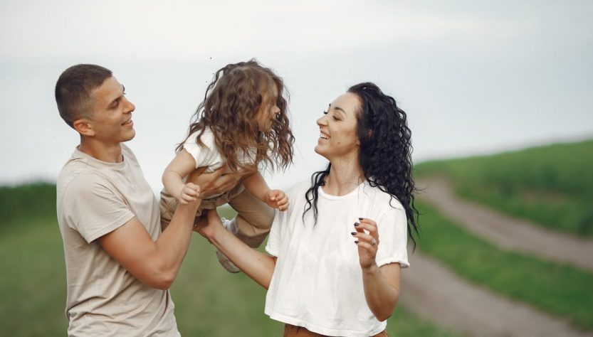 A joyful family moment outdoors with parents playing with their daughter.