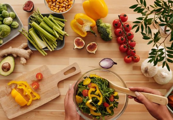 Top view of fresh vegetables and salad preparation on a wooden table, perfect for healthy eating concepts.