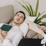 Thoughtful well dressed man with journal lying on sofa in office of modern female therapist and telling about problems