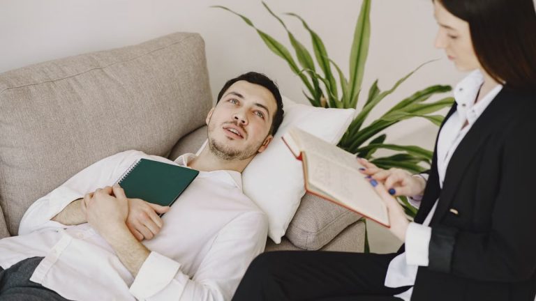 Thoughtful well dressed man with journal lying on sofa in office of modern female therapist and telling about problems