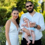 Charming family portrait of parents with a baby in a vibrant summer garden setting.