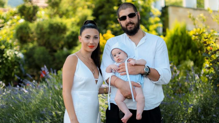 Charming family portrait of parents with a baby in a vibrant summer garden setting.